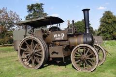 McLaren Road Locomotive – Gigantic, 10 NHP, Built 1912, Works No. 1332, Reg. No. DS 7128. Built as a batch of 5 engines for Port Adelaide Corporation in South Australia to haul 50 tons of gravel from a quarry for the construction of roads in the district. After just 3 years it was found that the quarry was being run at a loss and its contents were put up for auction and sold off. The engine ended up in Cal Lal alongside the banks of the River Murray. In the late 1960’s scrap men came across the engine and tried to buy it but were told it was not for sale. Instead they returned to the engine and stripped it of all its brass fittings and dynamited the cylinder off the boiler. The engine remained partially scrapped until 1978 when it was discovered by Maurice Taylor, a friend of UK based engine owner Brian Hardy from Sheffield. Brian managed to buy the engine for £50 and placed it in a container and shipped it back to the UK. Meanwhile Maurice, Brian’s friend also managed to find a replacement cylinder situated in New Zealand. The cylinder was also purchased by Brian and once back in the UK restoration started. The replacement cylinder although it fitted the boiler barrel was actually from a McLaren Direct Ploughing engine and bore sizes were equivalent to a standard 8nhp. Brian took a year off of work and with help from his father in law managed to return it back to steam in 1982. In 1988 Brian sold the engine to Mike Hibble who after a short amount of time sold it onto Tony Warwick, later that year. Tony rallied the engine around this area and named it “Gigantic”, carrying out much work over the years. In November 2012 the engine was bought by the present owners who totally stripped the engine and instructing Alan Davenport, a very well respected pattern maker, to produce a new 10NHP cylinder pattern. A new cylinder was cast in June 2013 along with new trunk guides, crossheads and valves. Over the last 18 months the present owners have machined and fitted the new cylinder and manufactured a complete new set of motion work and new gears and bearings. The engine has been finished in World War One drab green to represent one of the lost 55 10NHP engines built by McLaren for the War Department. Given that 2014 is the centenary of the start of the Great War, the present owners thought it would make a fitting tribute to the men and engines involved and lost during the conflict. 
Owned and driven by N. & T. Gough